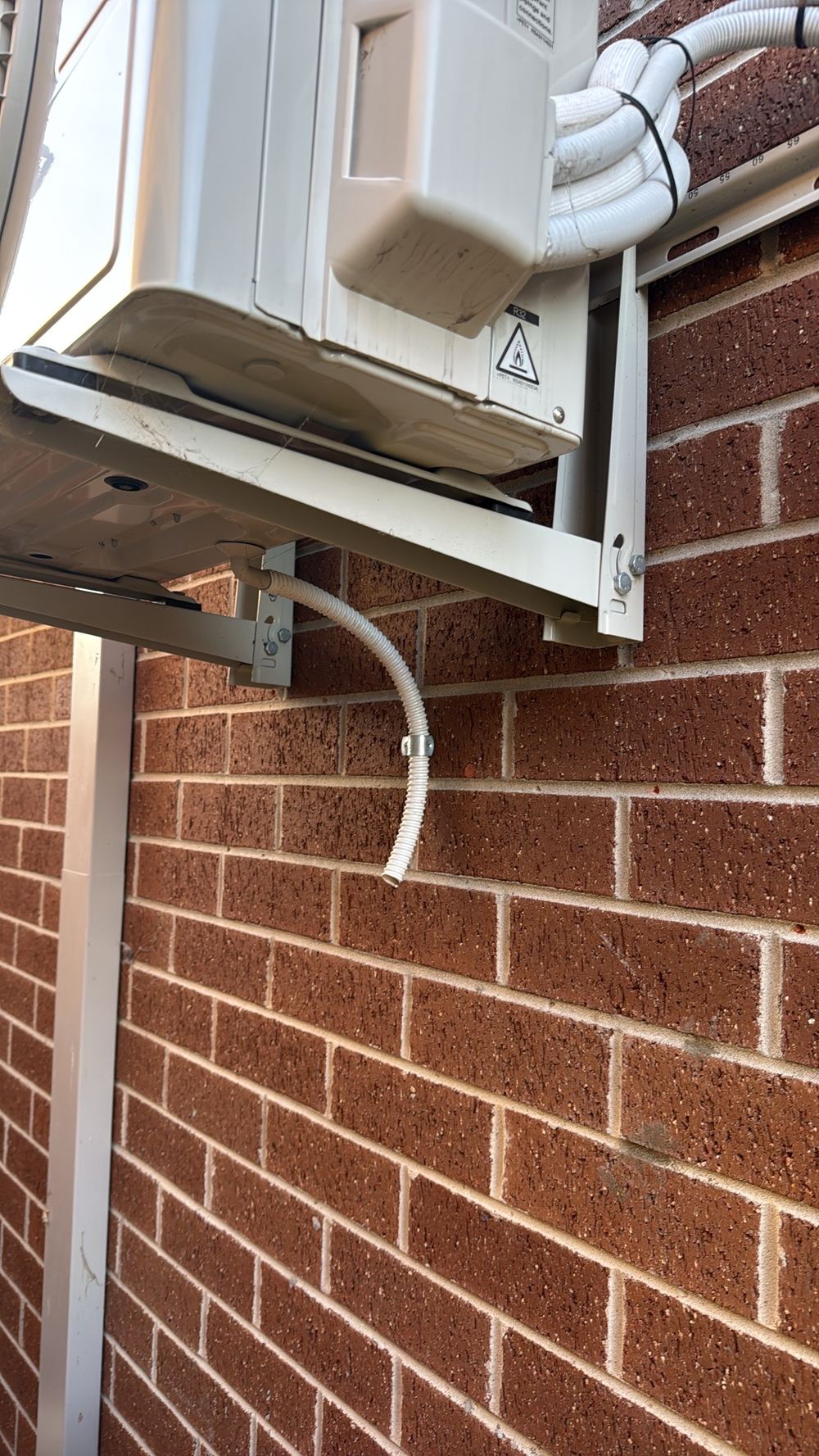 A second unit discharging condensate freely beside the brickwork, found during a building and pest inspection in Officer