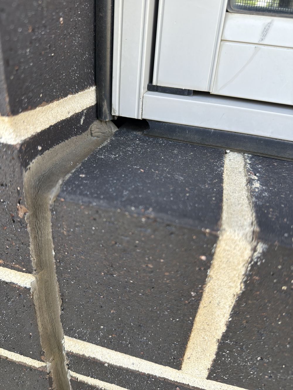 Gaps where window flashings meet the brick sill, letting wind-driven rain behind, found during a pre-purchase inspection in Officer