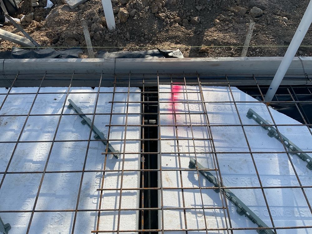 Reinforcement sitting low where bar chairs are needed to lift it clear, found during a slab pre-pour inspection in Officer
